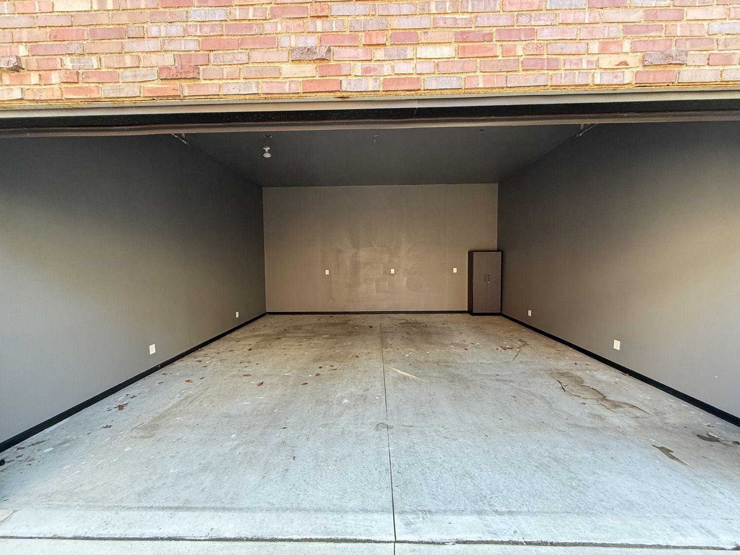 Empty two-car garage with a concrete floor and gray walls