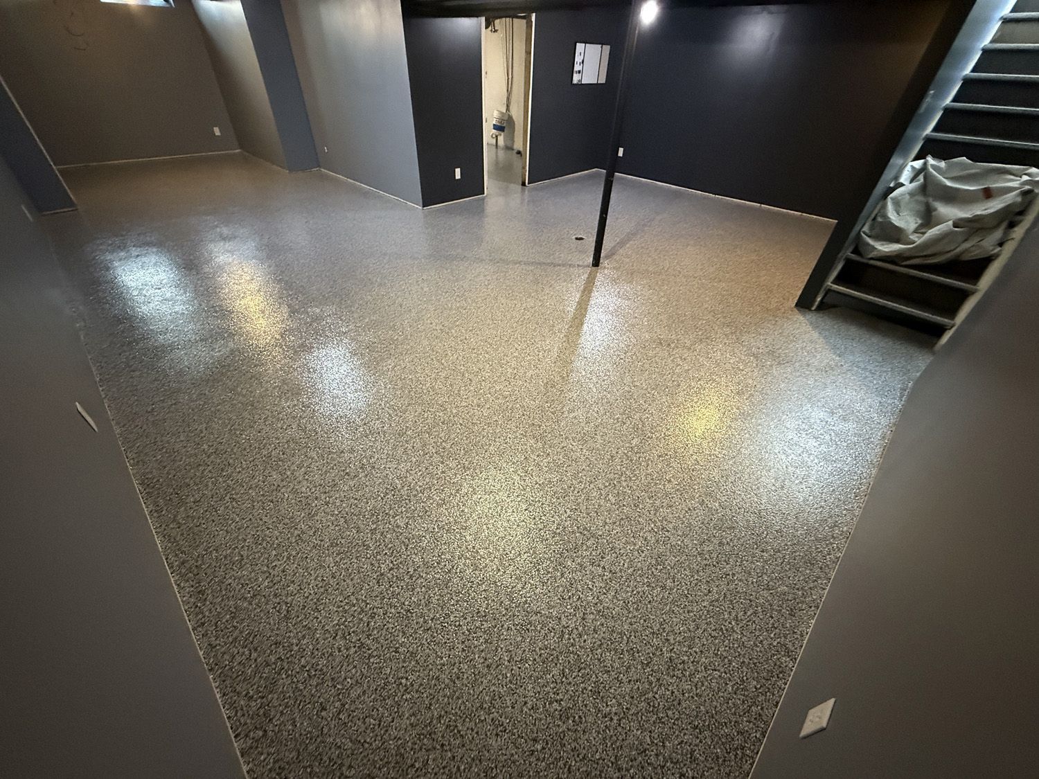 Empty hallway with dark walls and speckled flooring, viewed from a corner.