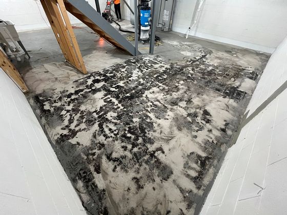 A dirty floor with a staircase in the background.