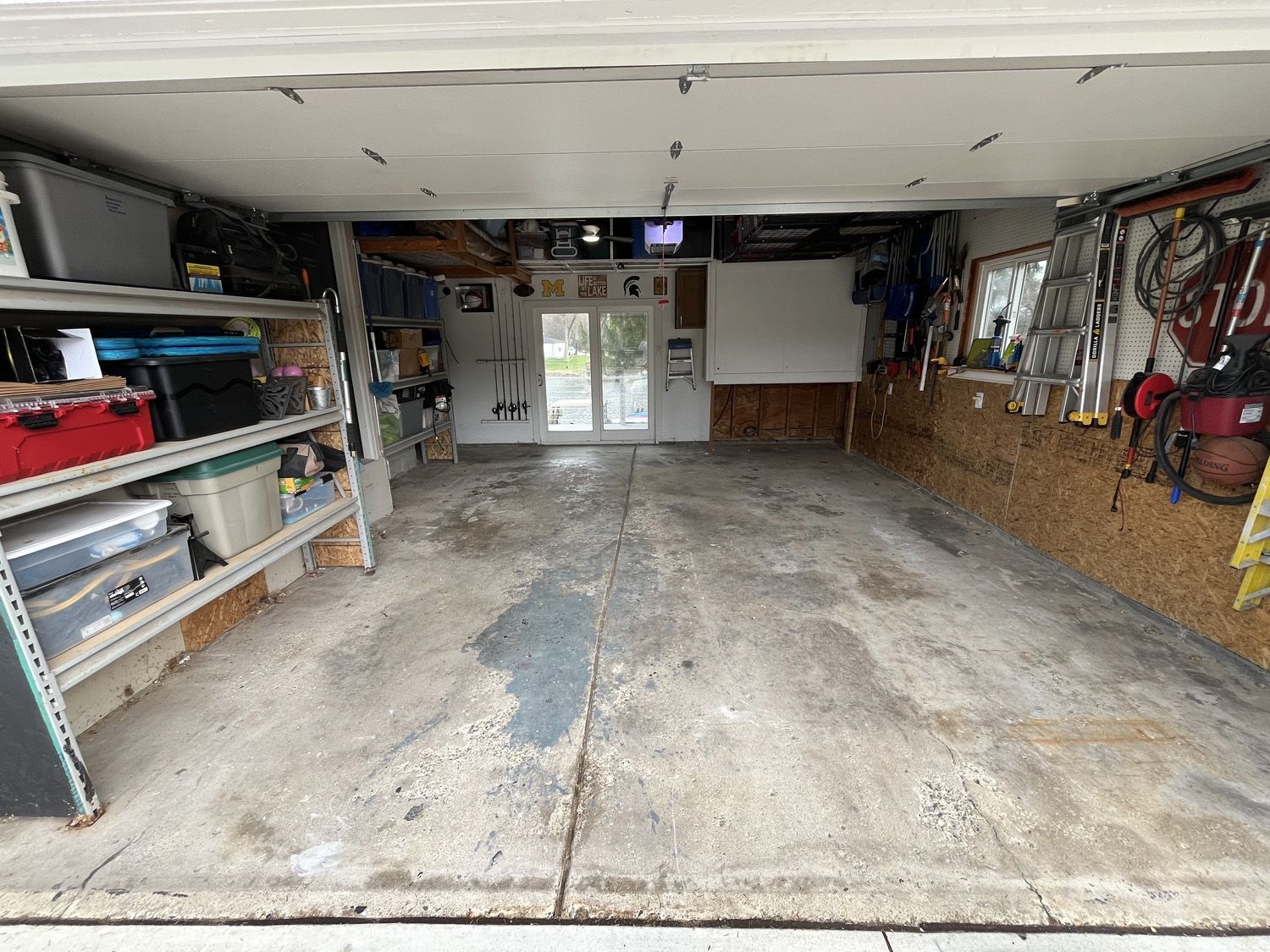 Empty garage interior with shelves, tools, and a closed door at the back.