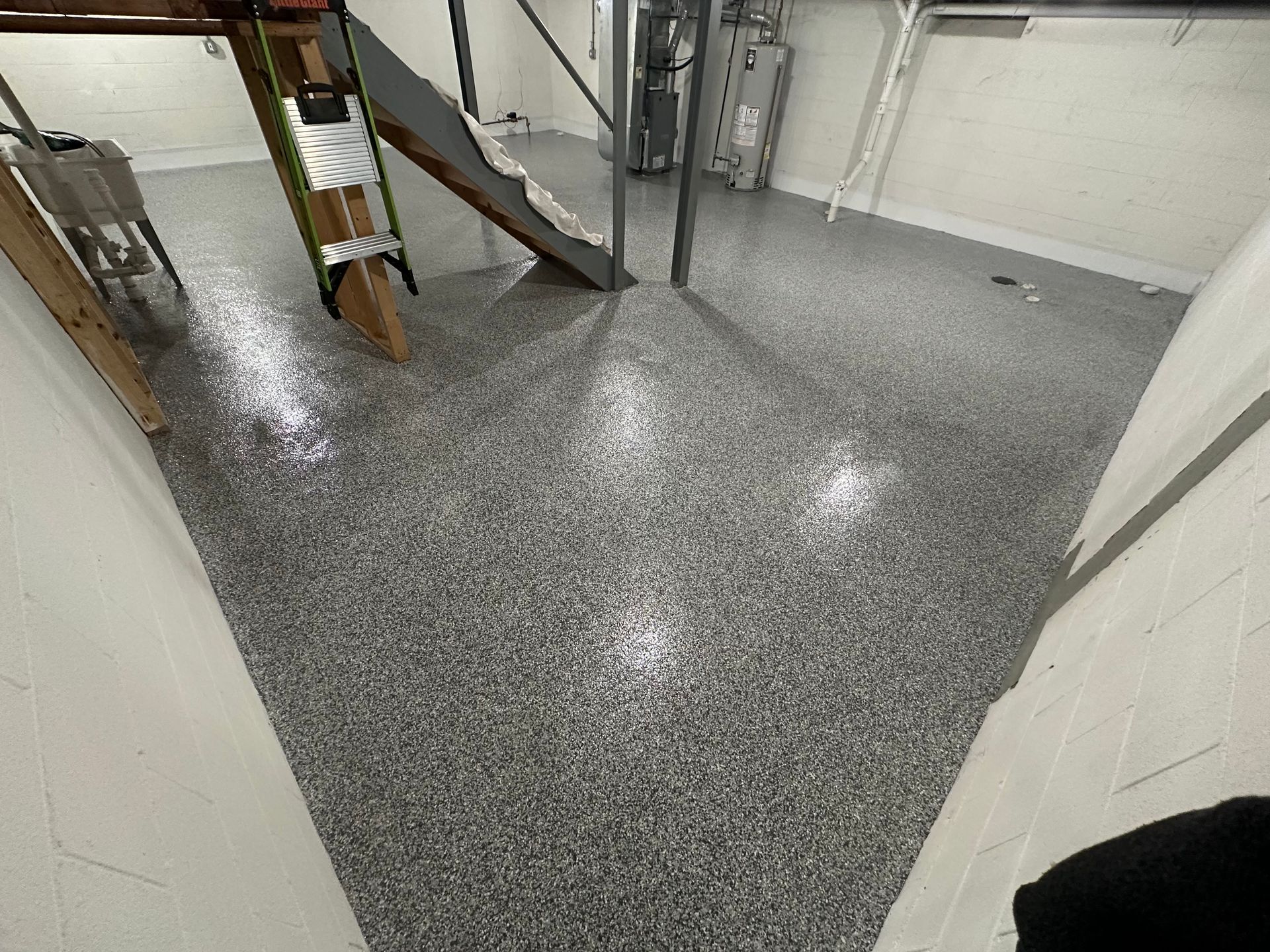 A person is standing in a basement with a ladder on the floor.