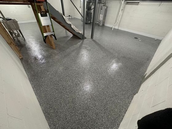 A person is standing in a basement with a ladder on the floor.