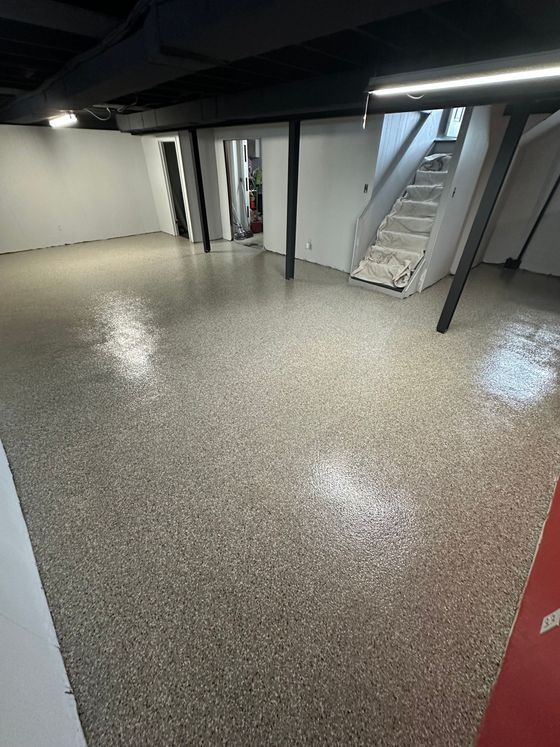 A basement with a staircase and a shiny floor.
