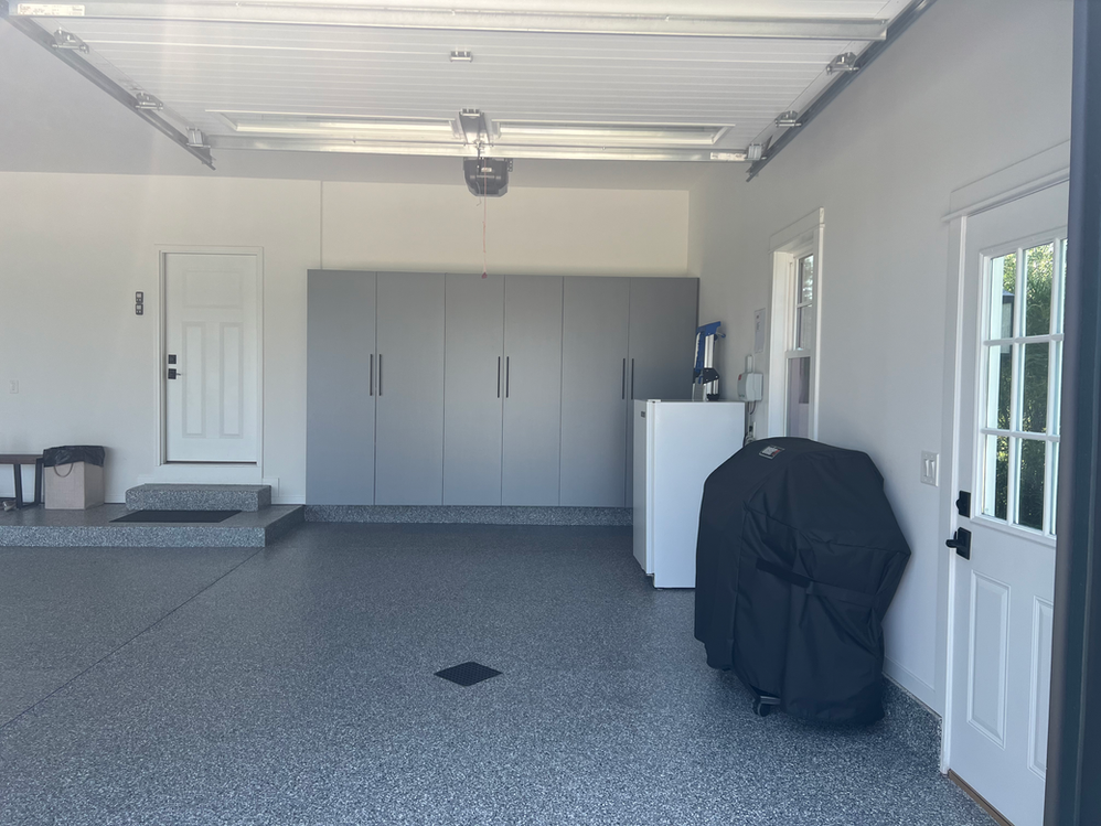 A garage with gray cabinets and a black grill.