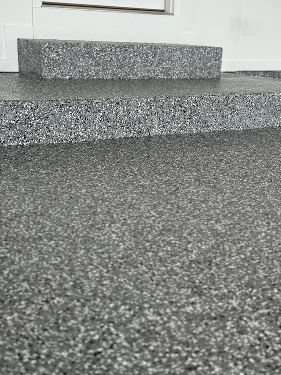 A close up of a gray carpeted floor next to a door.