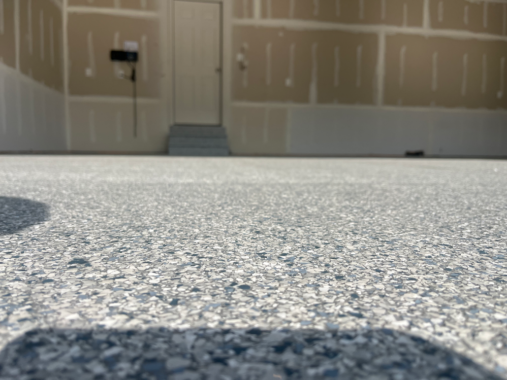 A close up of a garage floor with a door in the background.