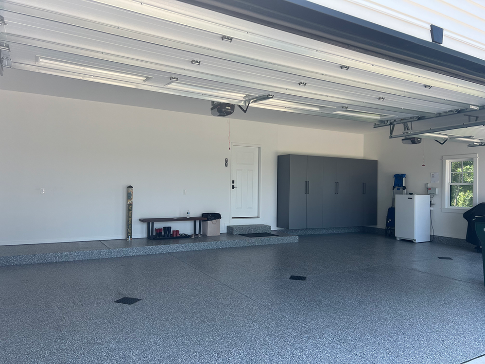 A garage with the door open and a bench in it