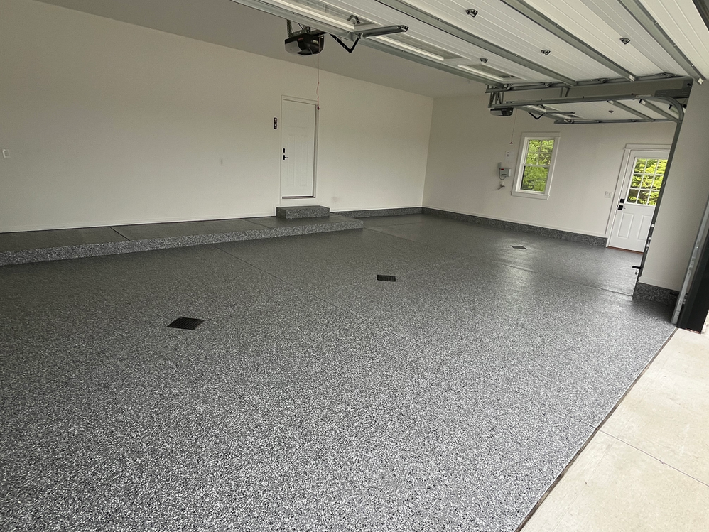 A garage with a garage door open and a gray floor.