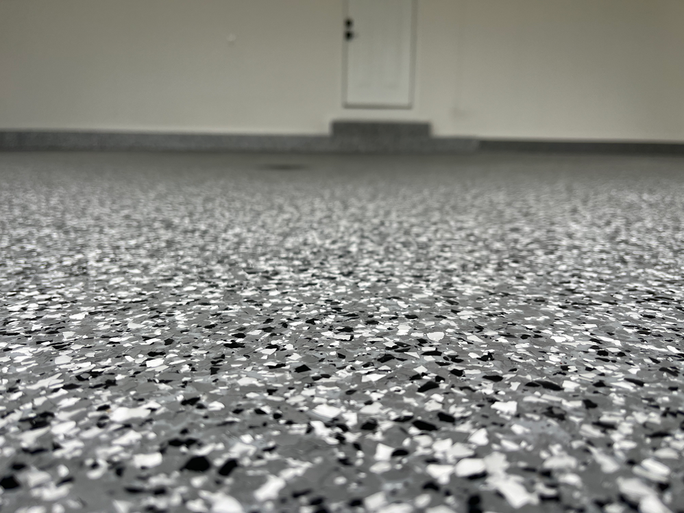 A close up of a gray and white flake floor in a garage.