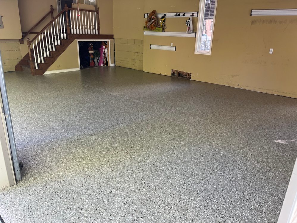 A garage with a staircase and a gray floor.