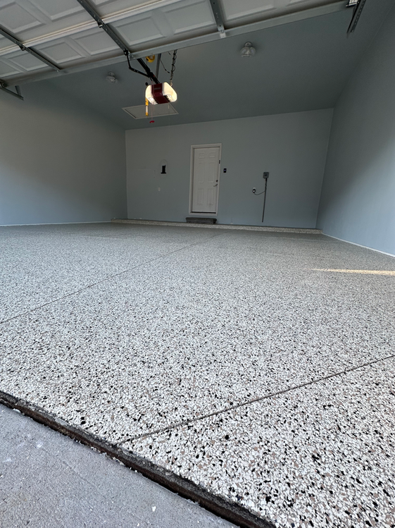 A garage with a gray floor and a garage door opener.