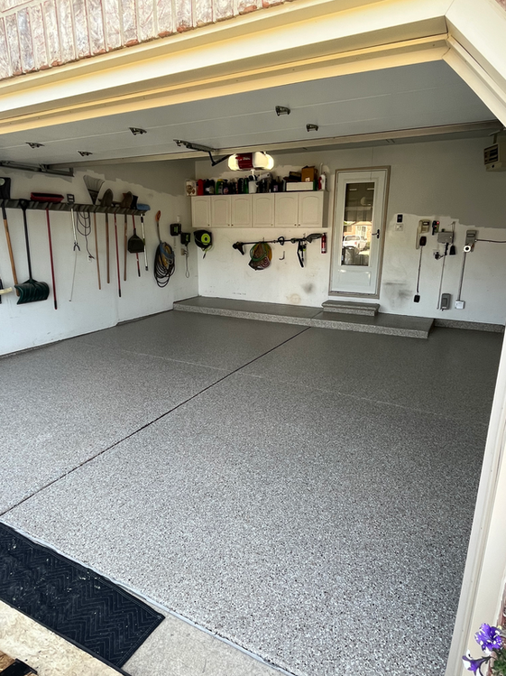 A garage with a concrete floor and a lot of tools on the wall.