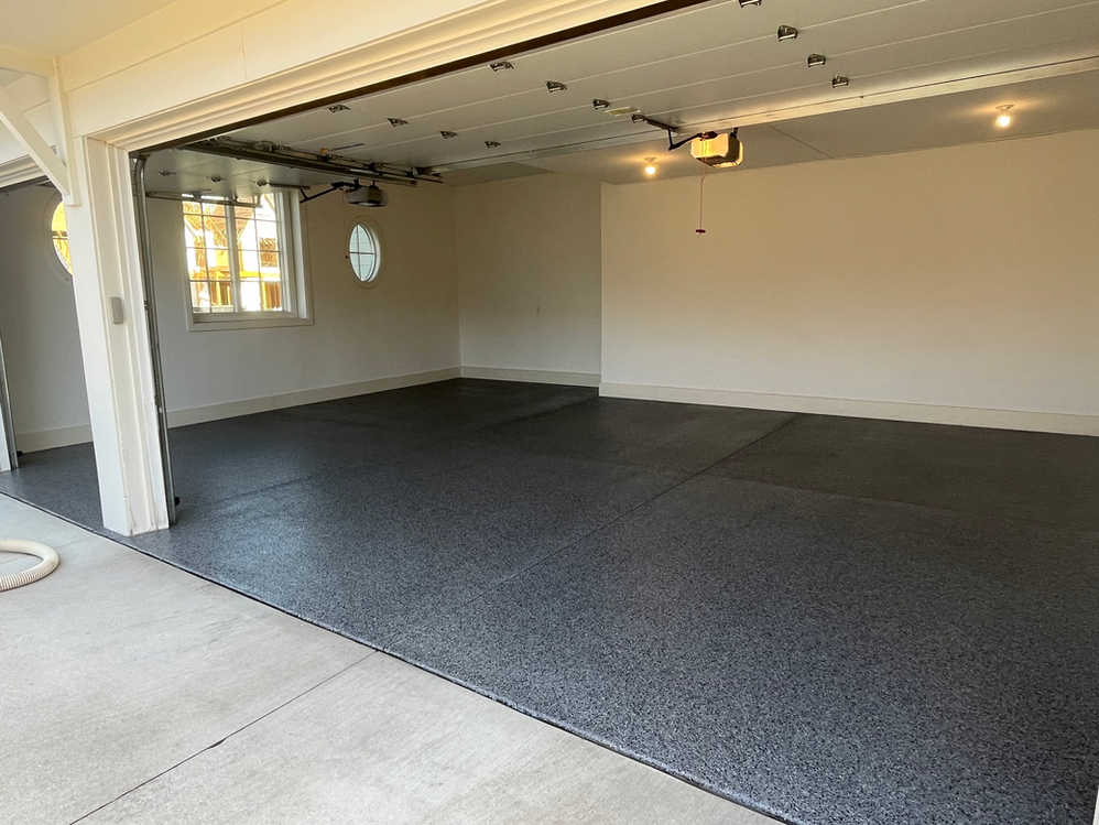 An empty garage with a garage door open and a window.