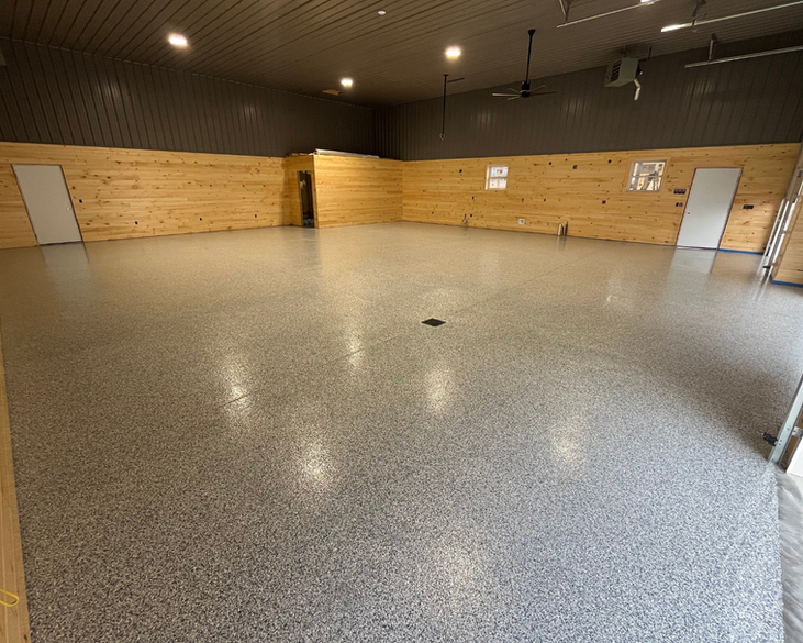 A large room with a gray floor and wooden walls