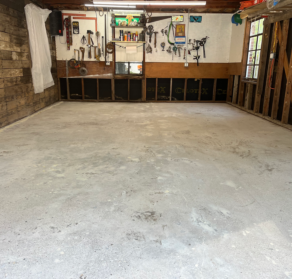 Empty garage workshop with concrete floor and tools hanging on the back wall