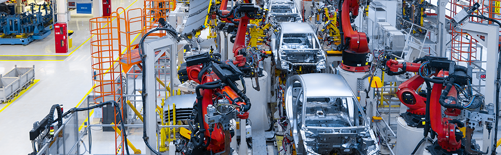 A row of cars are being assembled in a factory.