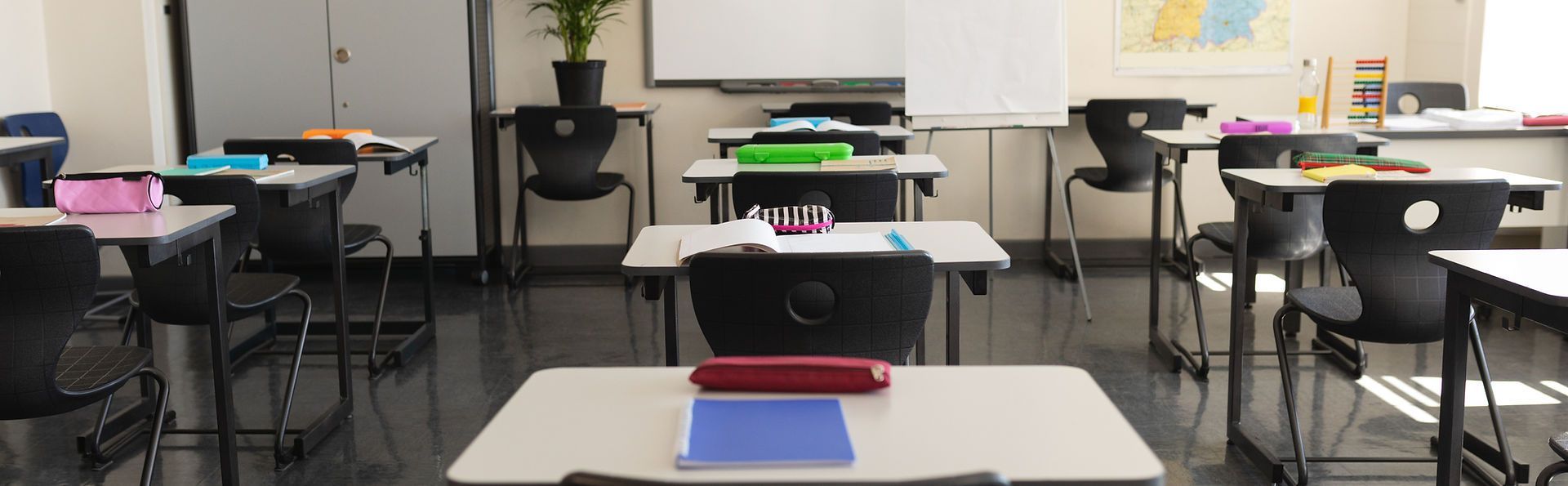An empty classroom with tables and chairs and a whiteboard.