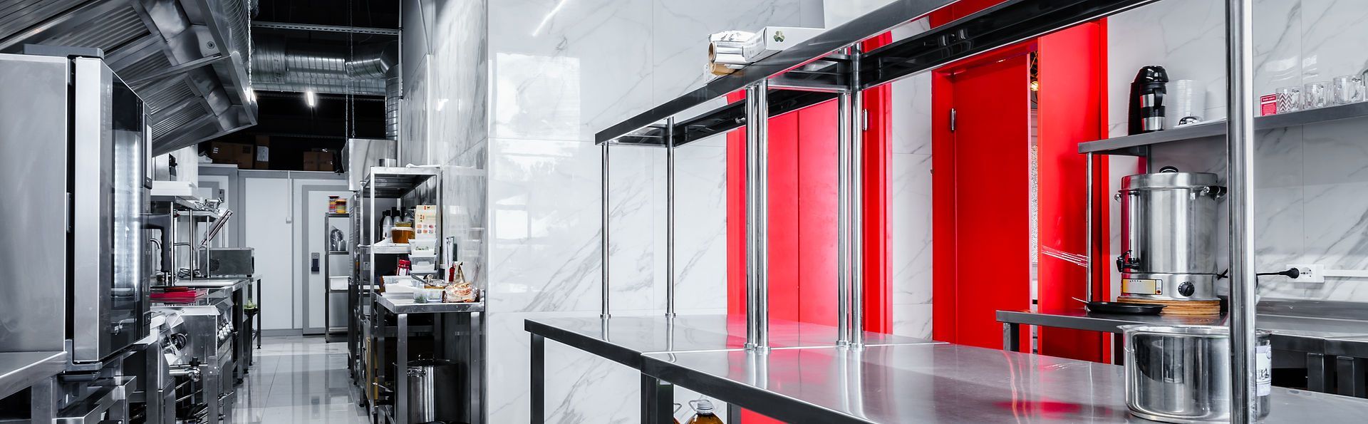 A kitchen with a lot of stainless steel appliances and a red door.