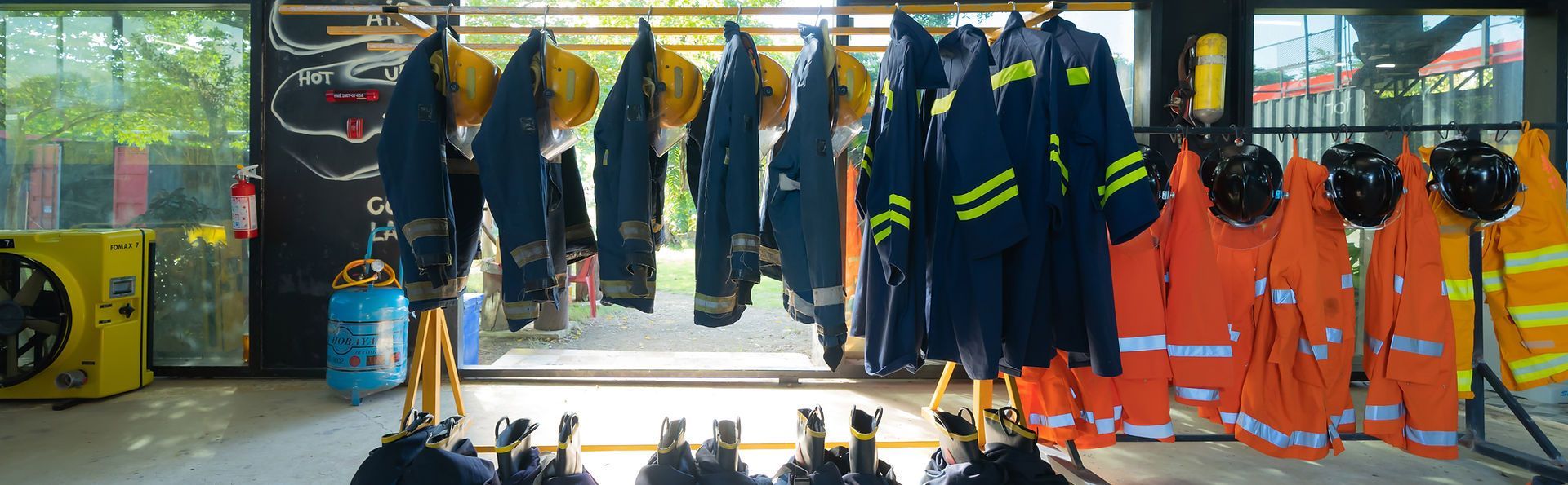A room filled with lots of clothes and helmets hanging on racks.
