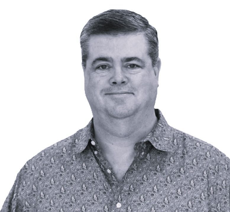 Portrait of a smiling man in a patterned button-up shirt on a plain white background