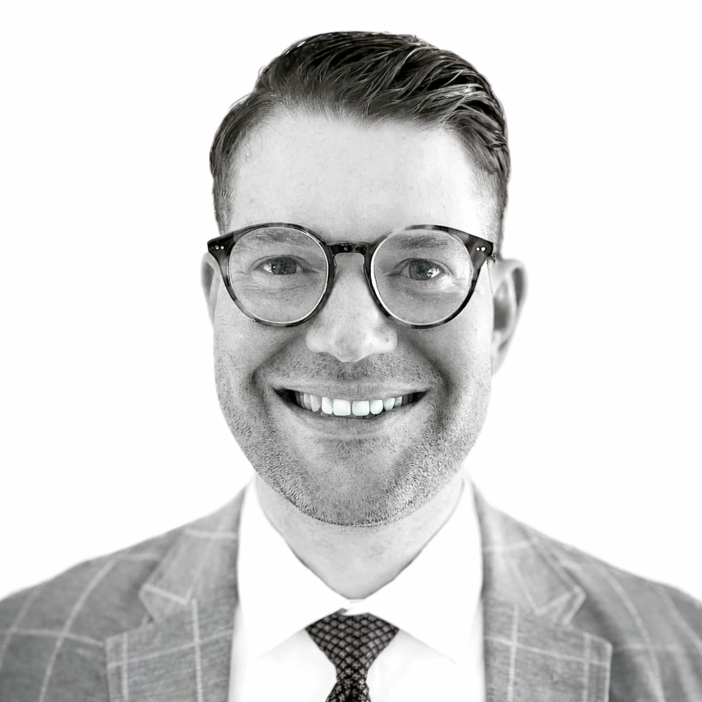Smiling man in glasses and suit against a white background