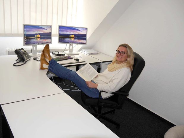Eine Frau sitzt mit hochgelegten Füßen auf einem Stuhl und liest ein Buch