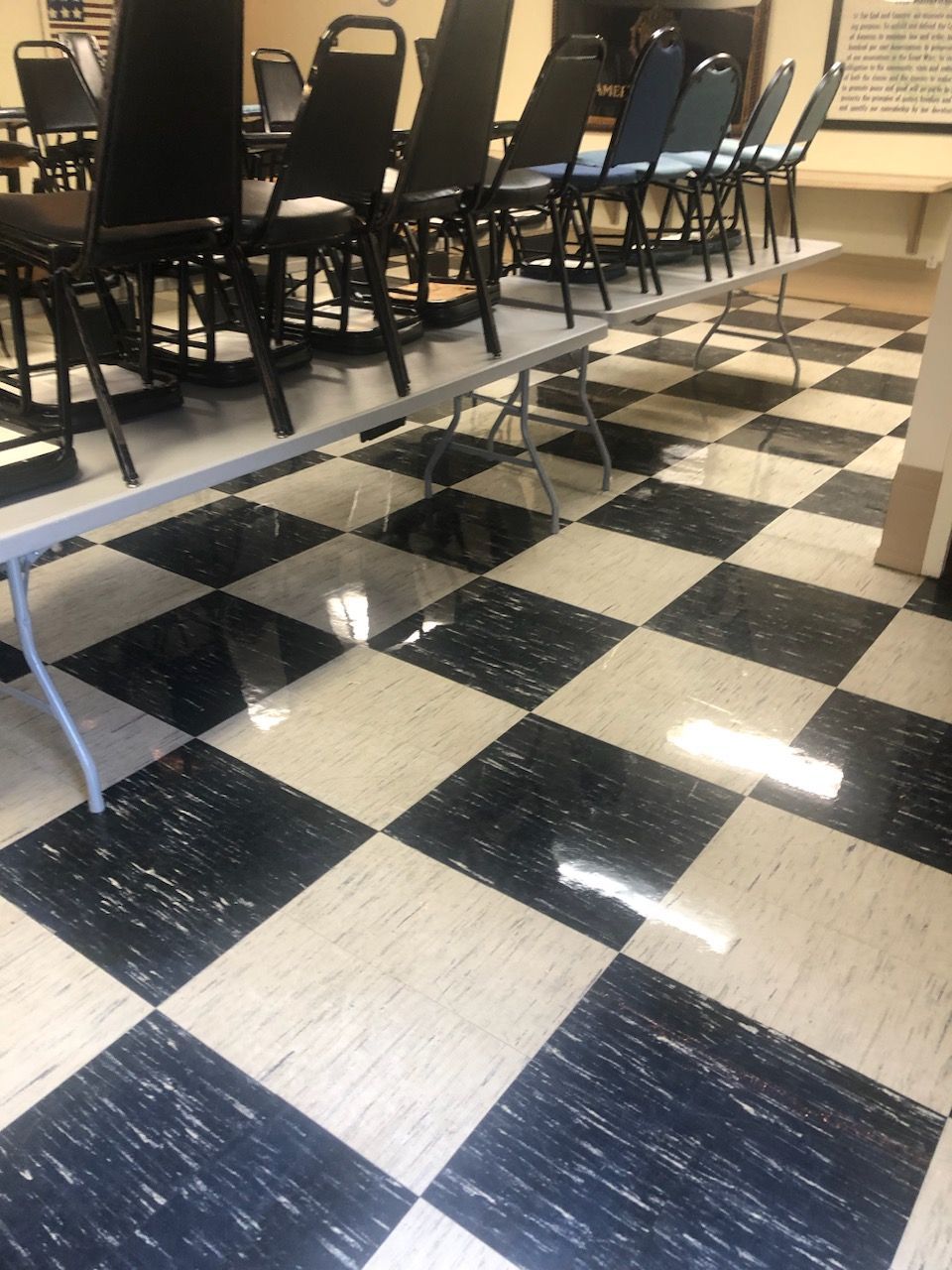 A row of black chairs placed on top of tables in a room with a black-and-white checkered tile floor.