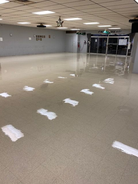 An indoor commercial space with a polished, reflective floor featuring white painted markings arranged in rows.
