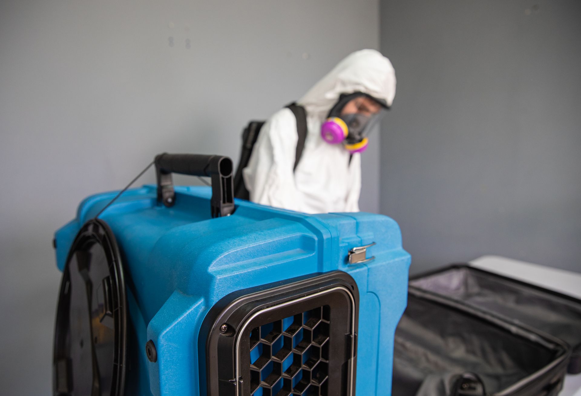 A man in a protective suit is standing next to a blue box