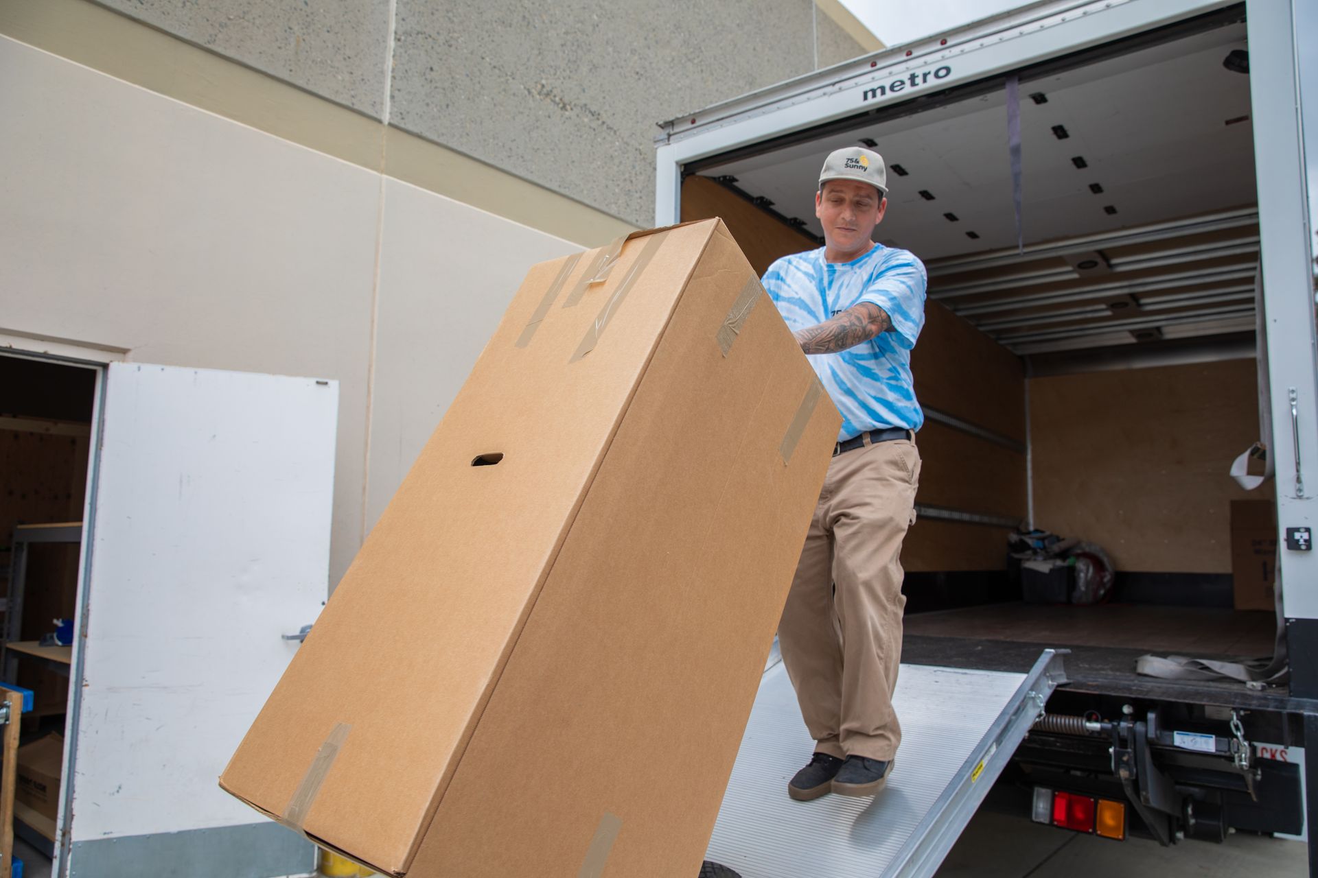 A man is loading a large cardboard box into a truck