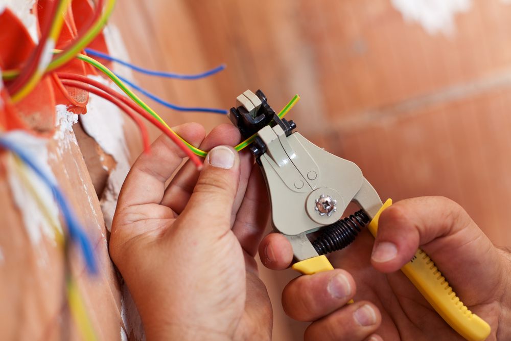 A Person Is Using A Wire Stripper To Cut A Wire  — Greg Keft Electrical in Port Macquarie, NSW