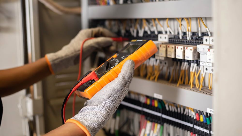 A Person Is Using A Multimeter To Test A Circuit Board — Greg Keft Electrical in Kempsey, NSW
