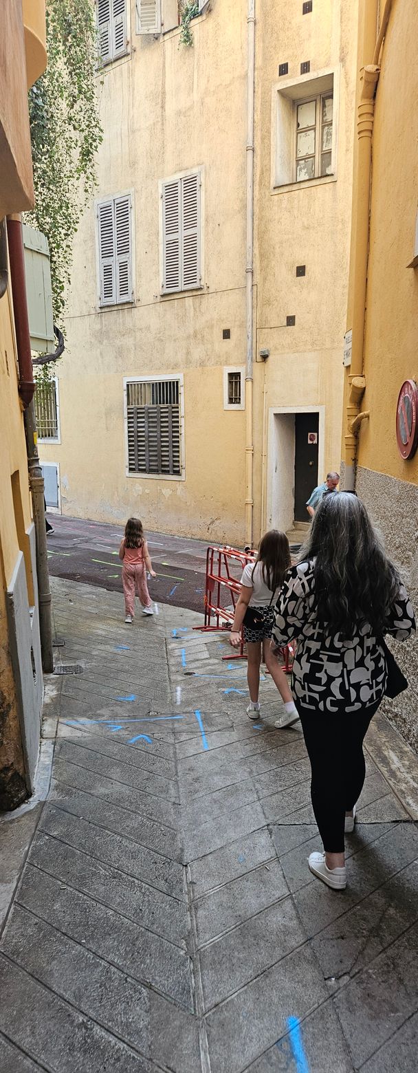 People walk up a narrow stone alleyway with buildings on both sides.