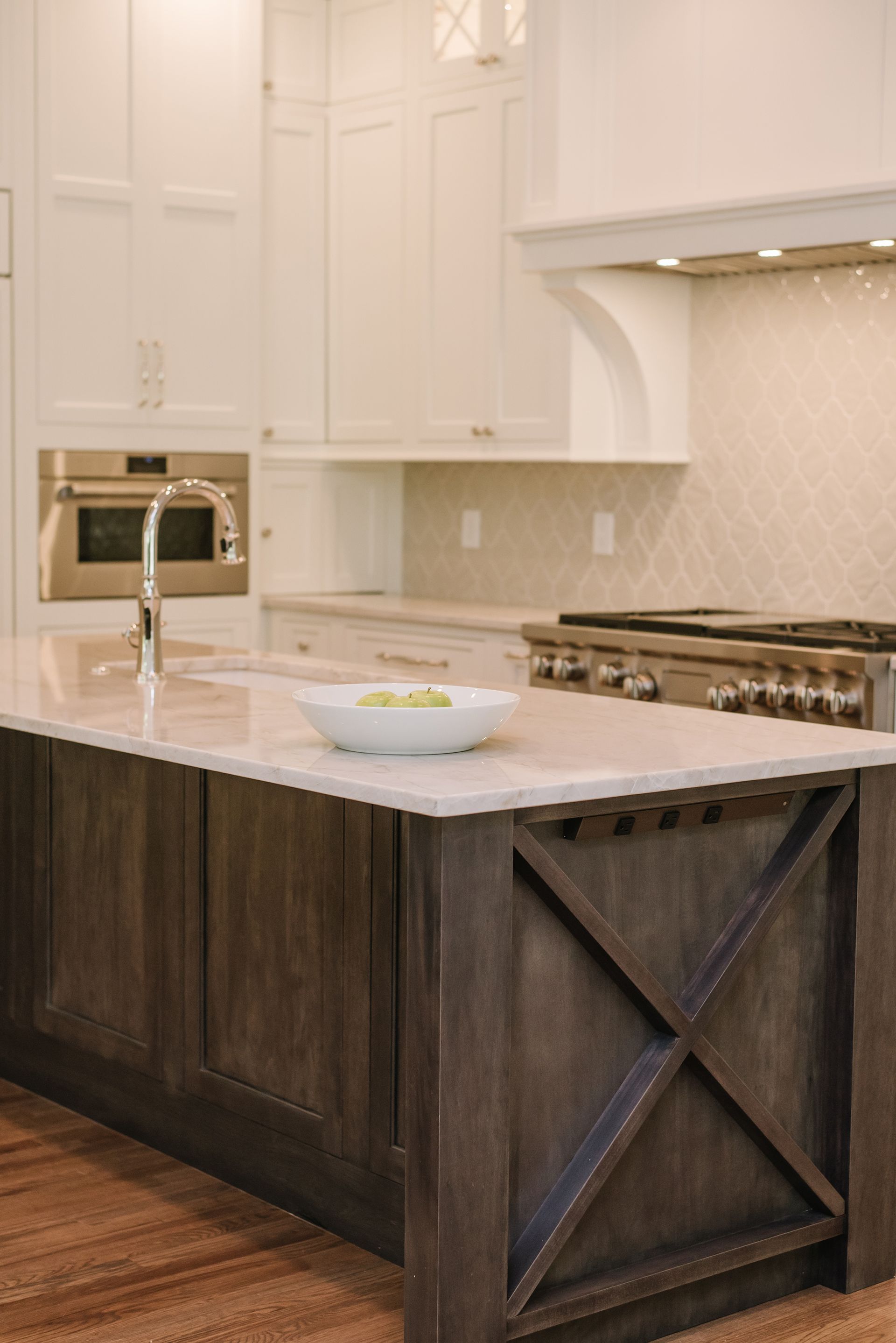 Kitchen island with dark wood base, white countertop, and light-colored cabinetry.