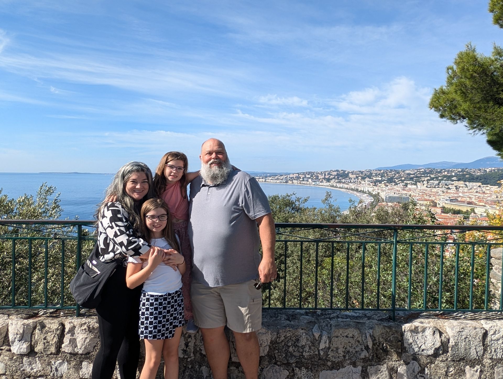 Family poses by a seaside city with a light blue sky.