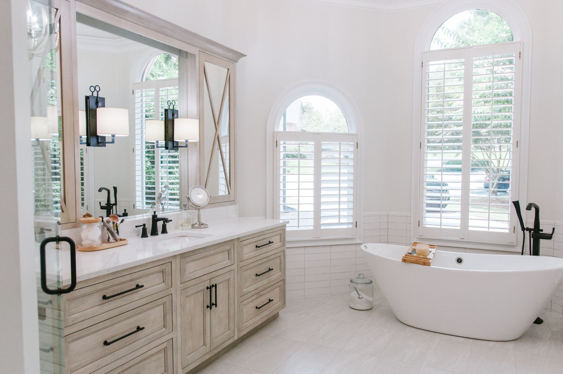 Bright white bathroom with a vanity, large mirror, and freestanding tub.