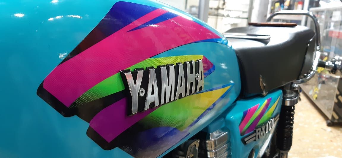 Primer plano del panel lateral de una motocicleta Yamaha con gráficos en magenta, verde y azul