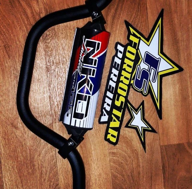 Manillar negro de BMX con pegatinas de Haro y Pro Star sobre un suelo de madera