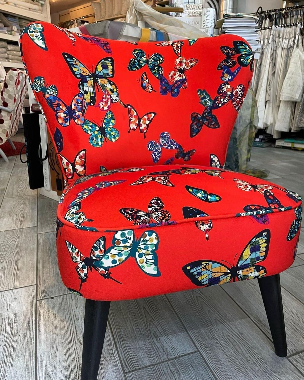 Carta da parati floreale con sedia e cuscino, accanto a una porta e a un mobiletto in legno.