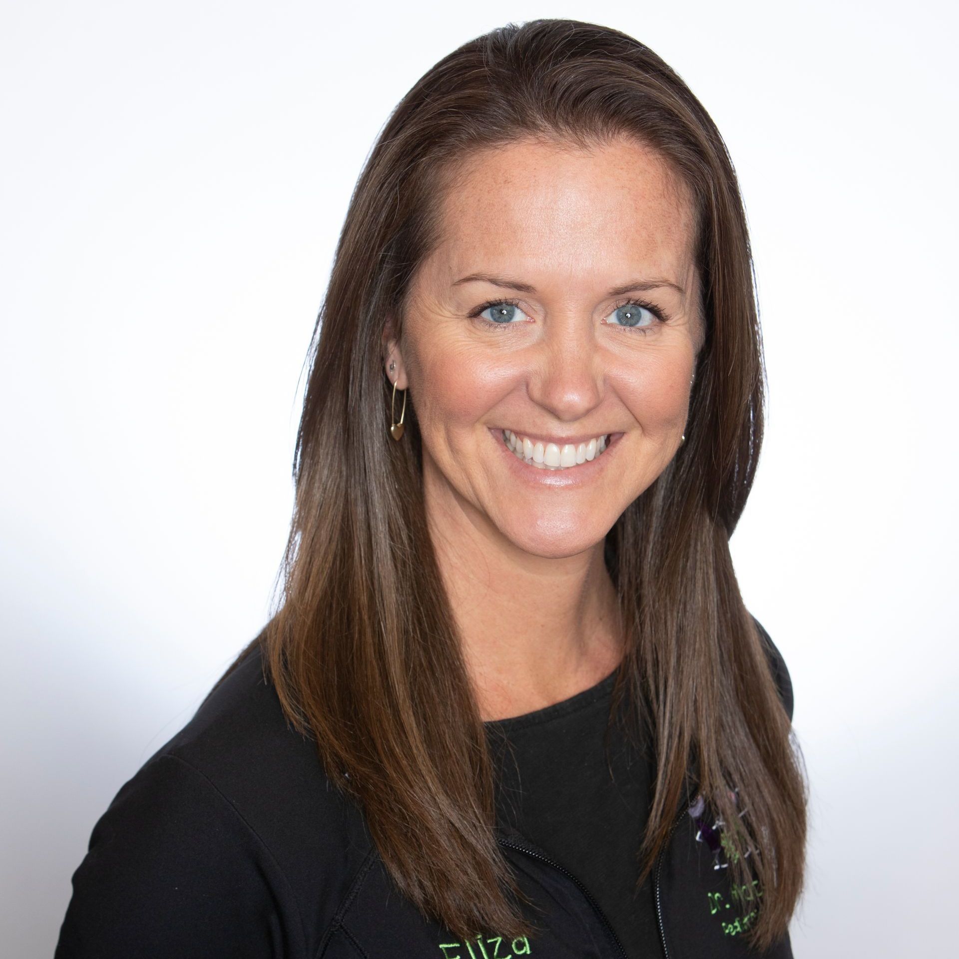 A woman with long brown hair and blue eyes is smiling for the camera.
