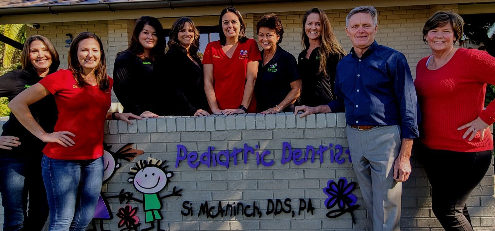 A group of people are posing for a picture in front of a brick wall.