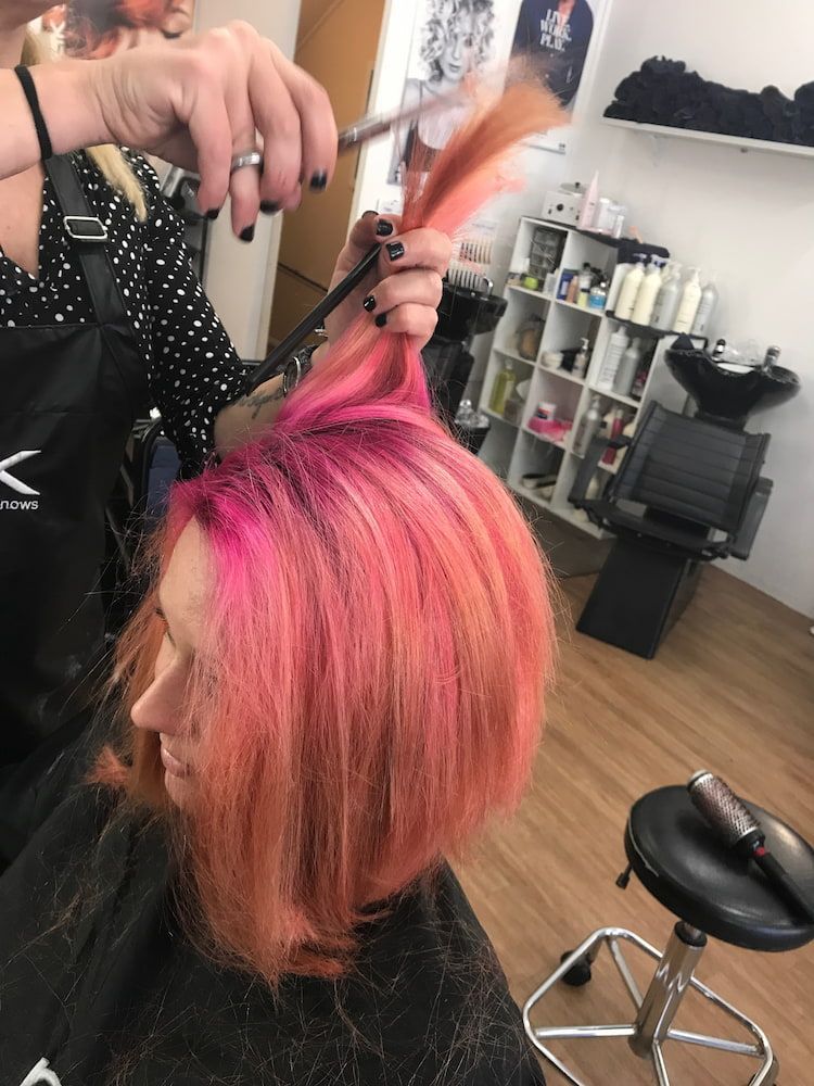 A Woman With Pink Hair Is Getting Her Hair Cut By A Hairdresser — Howard Street Hair Studio In Nambour, QLD