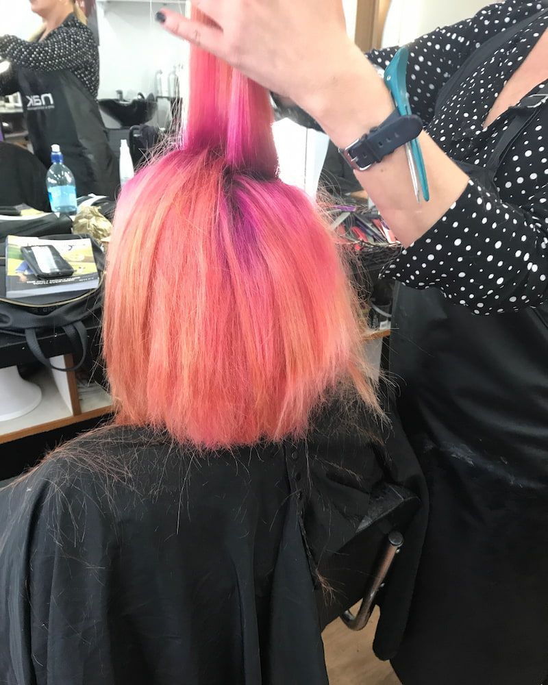 A Woman With Pink Hair Is Getting Her Hair Cut By A Hairdresser — Howard Street Hair Studio In Nambour, QLD