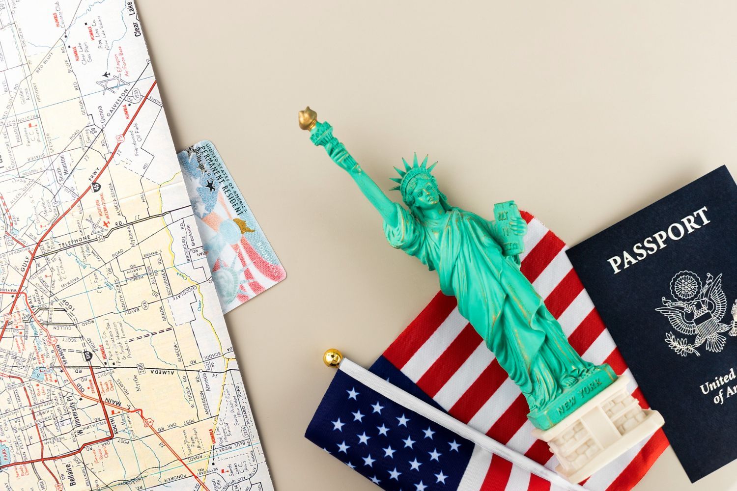 Travel items with U.S. flag, passport, Statue of Liberty figurine, and map on a light background