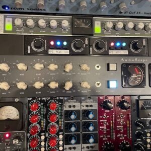 A rack of professional audio recording equipment, including compressors, preamps, and equalizers with knobs and meters.