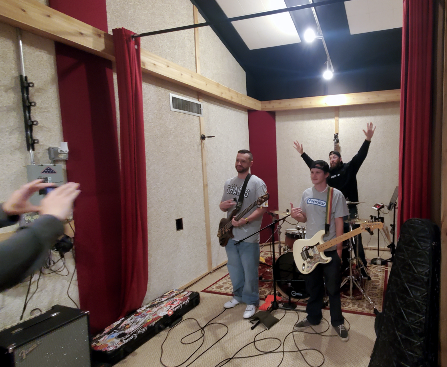 Band members posing for photo, one person with his arms up, others holding their guitars