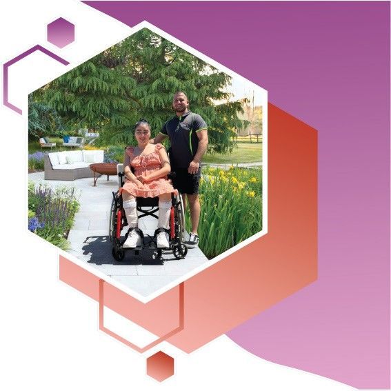 A man is standing next to a woman in a wheelchair.