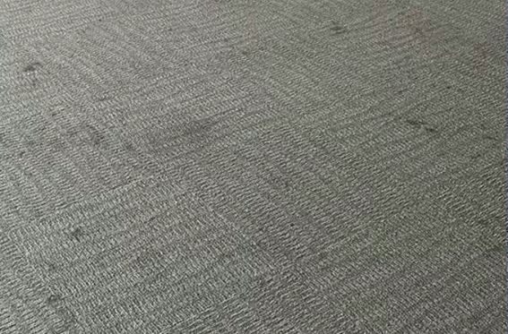 A close up of a gray carpet with a herringbone pattern.