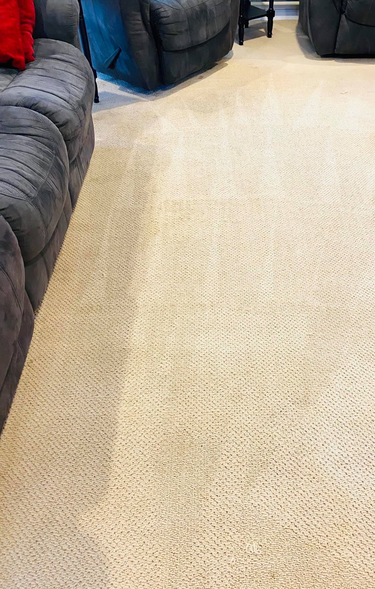 A living room with a couch and chairs and a rug on the floor.