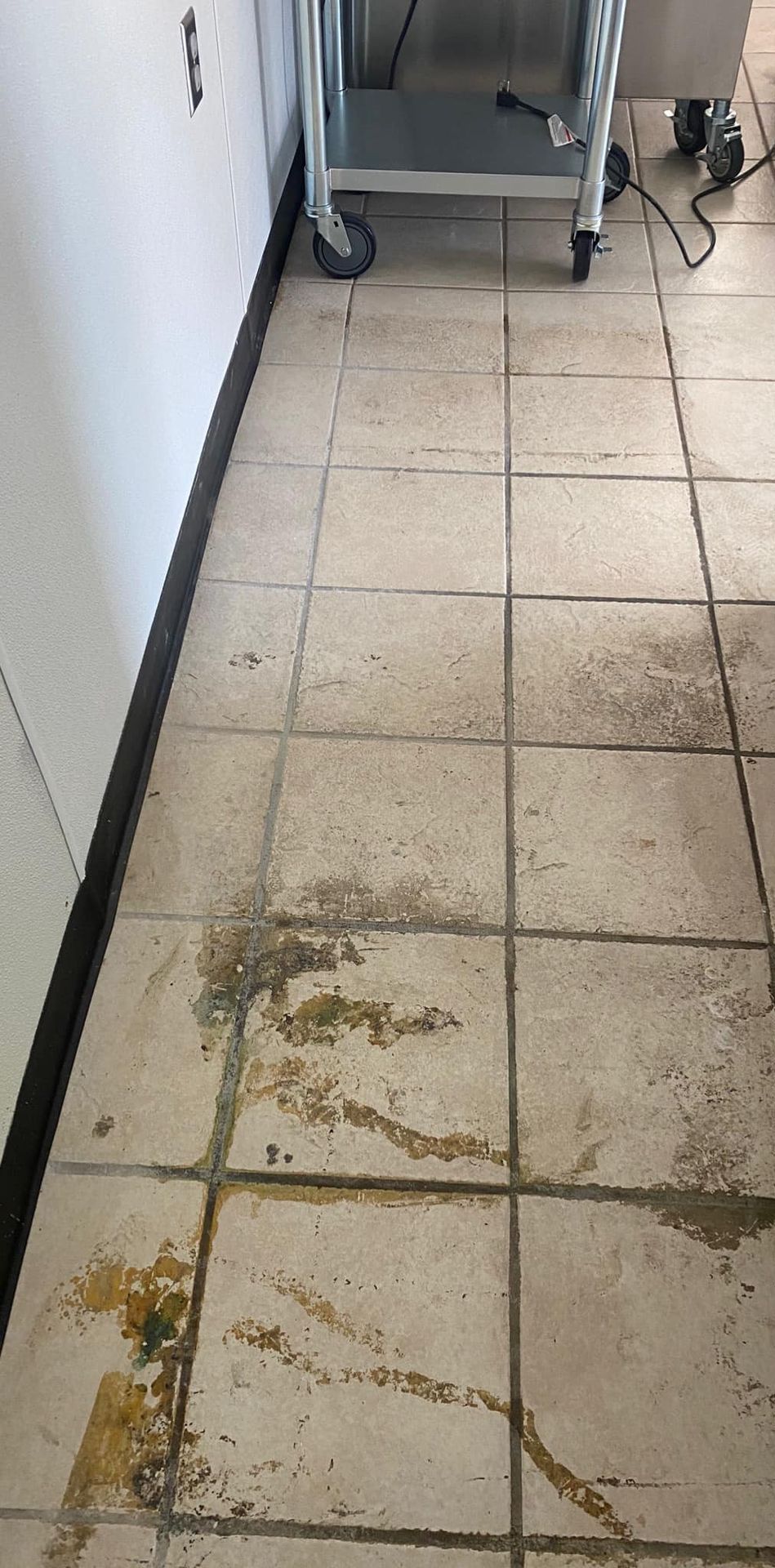 A dirty tiled floor with a cart in the background.
